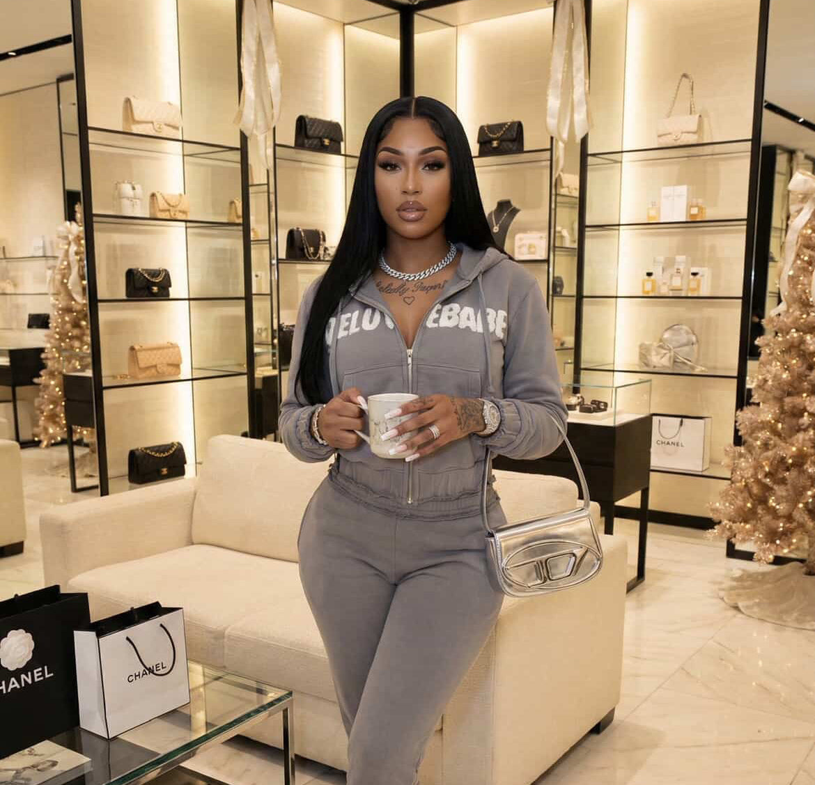 Woman in gray tracksuit holding a coffee cup in a stylish interior setting